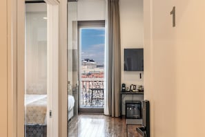 A hotel room with a bed, a balcony with a view of a cruise ship, a TV, and a coffee maker. - Sette Stelle Suites (Naples)