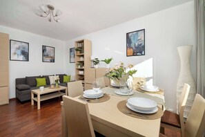 Ein modernes Wohnzimmer mit Essbereich, ausgestattet mit einer Couch, einem Couchtisch und einem Esstisch für zwei Personen.
