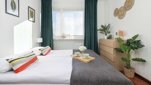 Quarto de hotel bem organizado, com cama, mesa de cabeceira, cômoda e janela com cortinas.