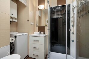 Ein modernes Badezimmer mit einer Duschkabine, einer Toilette, einem Waschbecken und einer kleinen Waschmaschine.