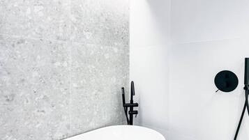 A bathroom with a white sink, a marble wall, and a black faucet.