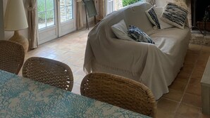 Une pièce chaleureuse avec un lit, des fauteuils en osier, une table et une cheminée.
