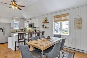 A kitchen with white cabinets, a wooden island, and a dining area with a table and chairs. - Sunrise Bay Cottage - Your Perfect Escape on Stoney Lake, 1.5 hrs from the GTA (Trent Lakes)