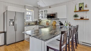 A modern kitchen with white cabinetry, a granite countertop, and a stainless steel refrigerator. - Sunrise Bay Cottage - Your Perfect Escape on Stoney Lake, 1.5 hrs from the GTA (Trent Lakes)