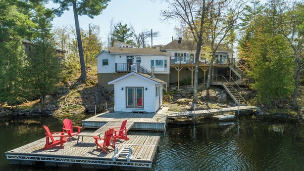 A lakeside cabin with a dock, red chairs, and a small cabin structure. - Sunrise Bay Cottage - Your Perfect Escape on Stoney Lake, 1.5 hrs from the GTA (Trent Lakes)