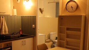 Una cucina compatta con zona pranzo, una sveglia e una piccola scaffalatura.