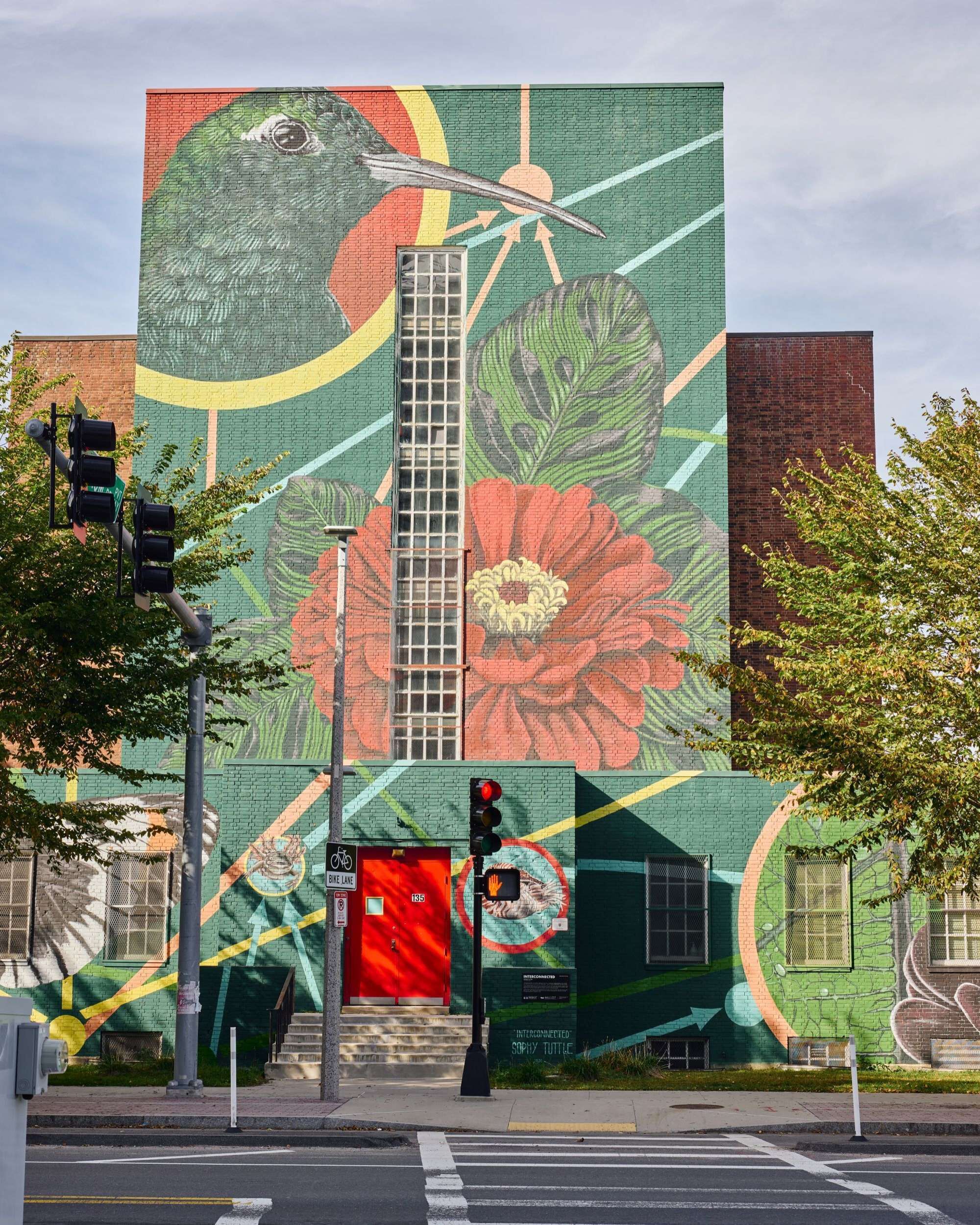 Un edificio con un gran mural que muestra una guitarra, flores y diseños abstractos.