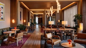 Un vestíbulo de hotel moderno con suelo de madera, varias zonas de estar e iluminación colgante.