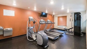 Centro de fitness com esteiras, bicicleta ergométrica e televisão na parede.