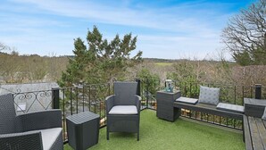 En uteplats med möbler i rotting, ett inbyggt bord och utsikt över det omgivande landskapet.