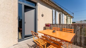 A balcony with a table and chairs, a door, and a fence. - Holiday Home 'La halte provençale - Cocooning' with Private Terrace, Wi-Fi & Air Conditioning (Châteaurenard)