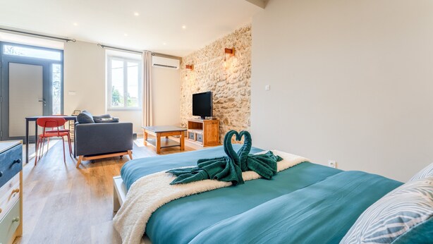 A bedroom with a bed, a TV, a stone wall, a desk, and a chair. - Holiday Home 'La halte provençale - Cocooning' with Private Terrace, Wi-Fi & Air Conditioning (Châteaurenard)