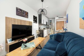 Un salon moderne avec un grand téléviseur à écran plat, une table basse en bois et un canapé bleu.