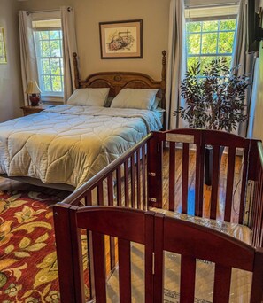 Un dormitorio con una cama, una silla de madera, una planta y una ventana.