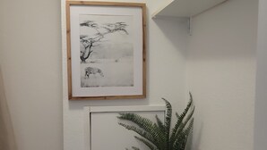 Un bagno con un water, un quadro che raffigura una zebra, una pianta e un cestino con carta igienica.
