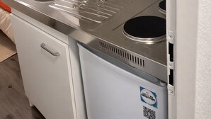 Una piccola cucina compatta con lavello in acciaio inossidabile, un piano cottura e un frigorifero.