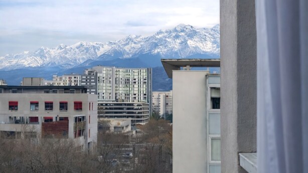 Vista dalla finestra su una città con montagne innevate sullo sfondo.