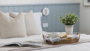 A neatly arranged bed with a book, a basket with cookies, a teapot, and a potted plant. - Dutchies Getaway – Elegant Family Home by the Water (Nelson Bay)