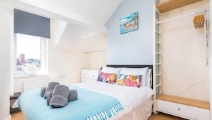 Une chambre à coucher avec un lit, une fenêtre, un radiateur, une armoire et un tableau accroché au mur.