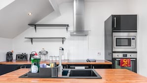 Une cuisine moderne dotée d’appareils électroménagers en acier inoxydable, d’un plan de travail en bois et d’un four encastré.