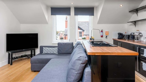 Un appartement moderne comprenant un espace de vie, une kitchenette et une grande fenêtre.