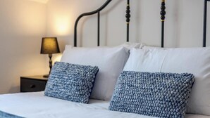 Una cama bien hecha con sábanas blancas y dos almohadas azules con textura.