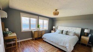 Un dormitorio con una cama grande, suelo de madera, un escritorio, una silla y una ventana con vistas.