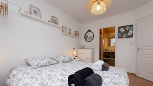 Een slaapkamer met een bed, kussens, een nachtkastje, een lamp, een kledingkast en een spiegel.