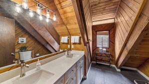 Een moderne badkamer met een grote spiegel, een dubbele wastafel en een douche.