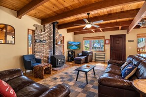 A cozy living room with a fireplace, leather sofas, a television, and a wooden ceiling. - Sierra Pines Cabin BBQ, Fireplace, Updated Kitchen (South Lake Tahoe)