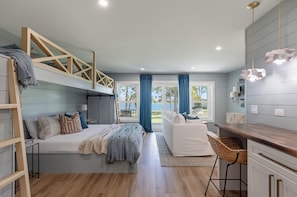 A modern bedroom with a bunk bed, a desk, and a view of the outdoors.