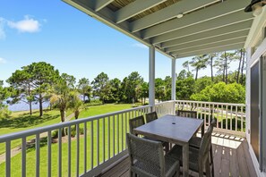 A covered outdoor area with a table and chairs, overlooking a well-maintained lawn and trees. - Making Memories, Beach, Golf Cart, Pool & Dock (Santa Rosa Beach)