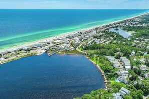 Vista aérea de un pueblo costero con playa, puerto deportivo y zonas residenciales.