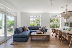 A modern living room with a sectional sofa, a coffee table, and a dining area with a chandelier. - Making Memories, Beach, Golf Cart, Pool & Dock (Santa Rosa Beach)
