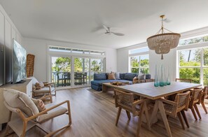 A spacious living area with a large sofa, dining table, and chairs, a television, and a ceiling fan. - Making Memories, Beach, Golf Cart, Pool & Dock (Santa Rosa Beach)