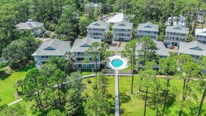 A resort with multiple buildings, a central pool, and a surrounding wooded area.