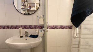 A bathroom with a white sink, a mirror, and a shower area. - Apartment in a quiet street (Schiltigheim)
