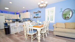 A kitchen with white cabinets, a dining table with white chairs, and a blue wall with 'Ocean City Maryland' decor. - Montego Bay-colonial Drive 13339 3 Bedroom Home (Ocean City)