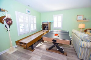 Une pièce avec une table de ping-pong, un banc, une petite table avec un haut-parleur et un canapé à rayures.