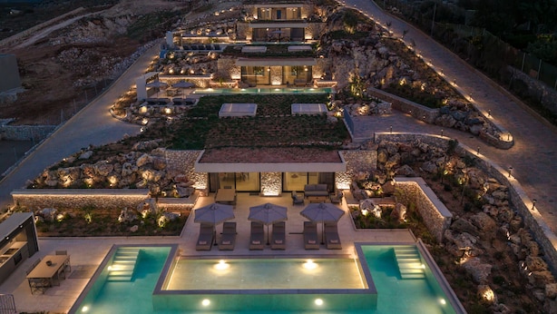 Um resort luxuoso com várias piscinas, áreas de estar ao ar livre e paisagem bem iluminada.