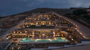 Um hotel com vários andares, piscina, área de estar ao ar livre e montanhas ao fundo.