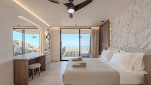 Quarto de hotel moderno com uma cama grande, uma escrivaninha e vista para o oceano.