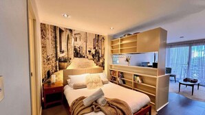 Un dormitorio moderno con una cama grande, una estantería empotrada y vistas a un paisaje urbano por la ventana.