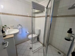 Une salle de bain avec une douche à parois de verre, un lavabo et des toilettes.