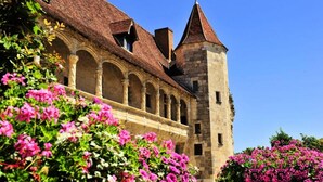A historic building with a central courtyard, arched windows, and a tower with a conical roof. - Apartment in Nerac Near Lud'o Parc (Nerac)