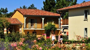 A two-story building with a balcony, surrounded by a garden with various plants and flowers. - Apartment in Nerac Near Lud'o Parc (Nerac)