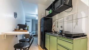 A compact kitchen with green cabinets, a black refrigerator, and a small countertop. - StayHome 1min da Praia | São Vicente SP | Família ou Casal (São Vicente)