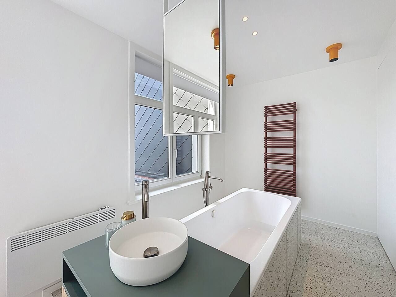 Une salle de bain moderne avec une baignoire sur pieds, un lavabo rond et un grand miroir.