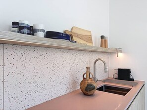 A kitchen with a speckled backsplash, a wooden cutting board, a vase, and a coffee machine. - Casa Vento -  Koksijde (Koksijde)