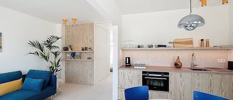 Eine moderne Küche mit Essbereich, ausgestattet mit einem weißen Tisch, blauen Stühlen und einem blauen Sofa mit gelben Kissen.